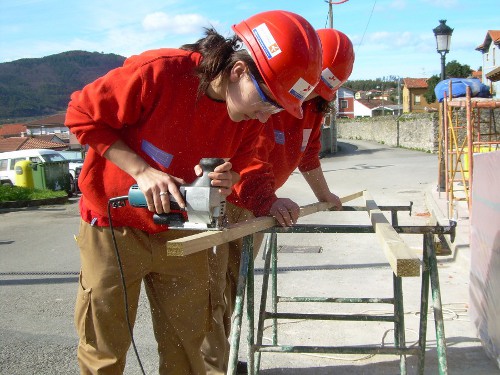 Alumnos de la Escuela Taller cortando madera.